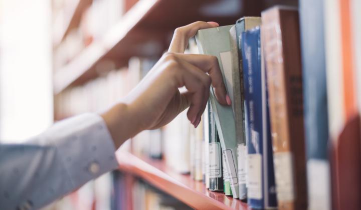 Picking a book from a library bookshelf